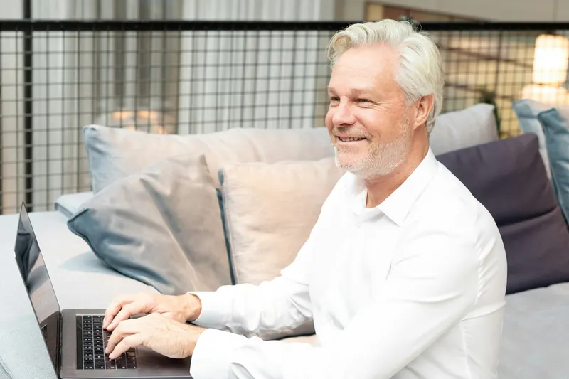 Selbständiger arbeitet am Laptop auf dem Sofa